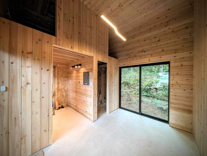 Wooden interior of a modern cabin with large windows and natural light.